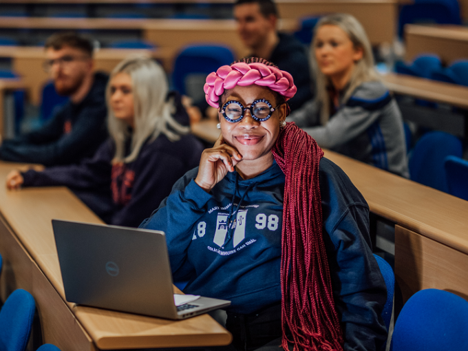 A female student is pictured sitting in front of laptop in a lecture room